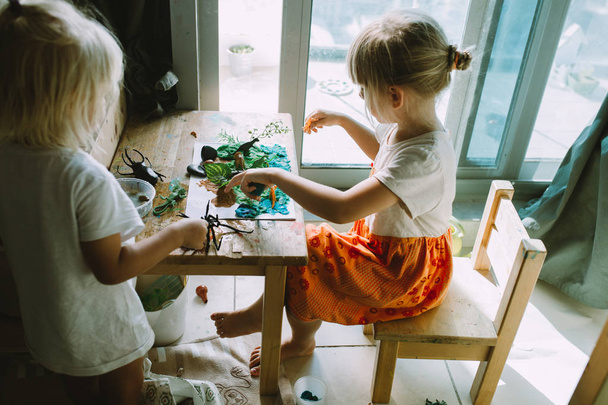 Portret van gelukkig schattige kleine meisjes tekenen met verf thuis, close-up - Foto, afbeelding