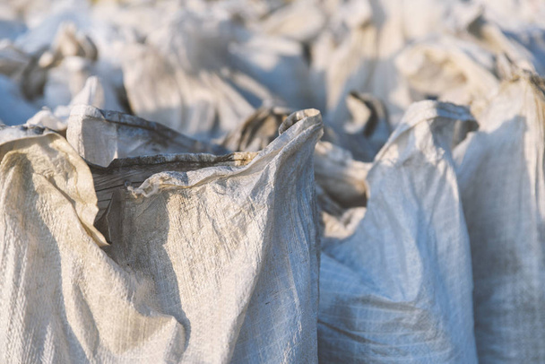 Gruppo di sacchi di plastica riempiti tessuti, imballaggio di merci per il trasporto e lo stoccaggio in un magazzino, sacchetti di polipropilene primo piano
 - Foto, immagini