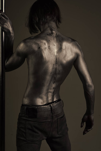 Guy puts hand on pole, rear view. Man with torso - 写真・画像