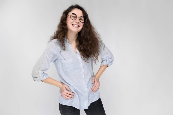 Young brunette girl with glasses. The girl put her hands on her hips. - Photo, Image
