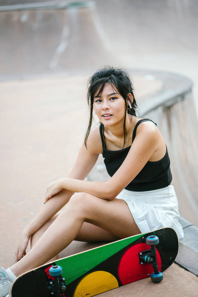 Portrait of Asian Chinese girl with mobile phone and skate in skatepark - Foto, afbeelding