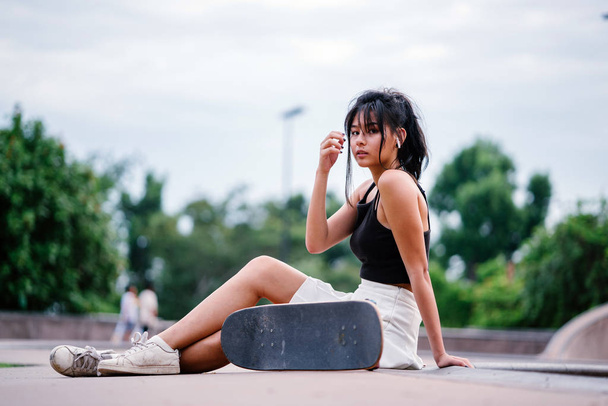 Portrait of Asian Chinese girl with mobile phone and skate in skatepark - Фото, зображення