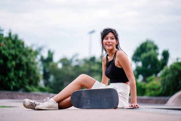 Portrait of Asian Chinese girl with mobile phone and skate in skatepark - Foto, Imagem