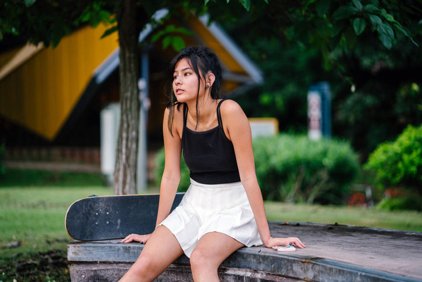 Portrait de fille chinoise asiatique avec téléphone mobile et skate dans skatepark
 - Photo, image
