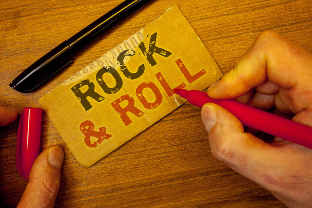 Schreibnotiz, die Rock "n" Roll zeigt. Business-Foto präsentiert Musikgenre Art der populären Tanzmusik Heavy Beat Soundman Erstellung auf gelbem Papier Hand hält rote schwarze Stifte Holztisch - Foto, Bild