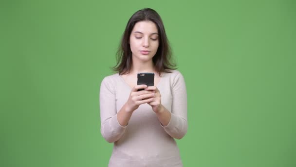 Young beautiful woman using phone against green background - Séquence, vidéo