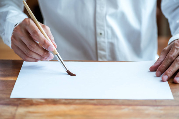 artist man hand using brush writing on blank white paper - Foto, Imagem