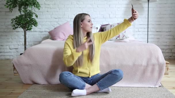 Cheerful attractive young woman taking selfie with mobile phone at home - Felvétel, videó