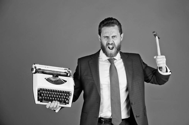 uusi teknologia. liikemies, aggressiivinen liikemies kirjoituskoneella ja vasaralla
 - Valokuva, kuva