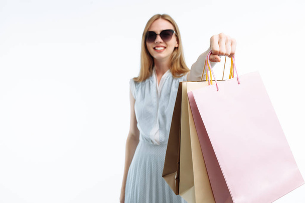 Young beautiful girl in glasses shopping, posing with gift bags, on white background, - Foto, imagen