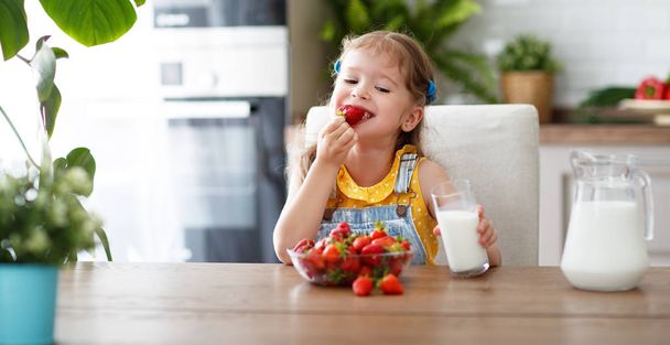niña feliz comiendo fresas con leche en hom
 - Foto, imagen
