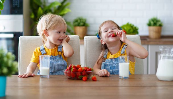 Bambini felici ragazza e ragazzo fratello e sorella mangiare fragole con mil
 - Foto, immagini