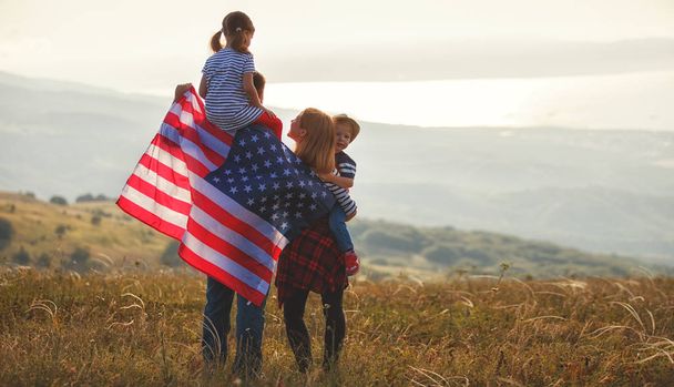 happy family with the flag of america USA at sunset outdoor - Foto, Bild