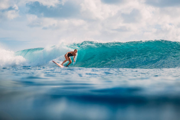 Hermosa chica surfista en tabla de surf. Mujer en el océano durante el surf. Surfista y ola
 - Foto, imagen