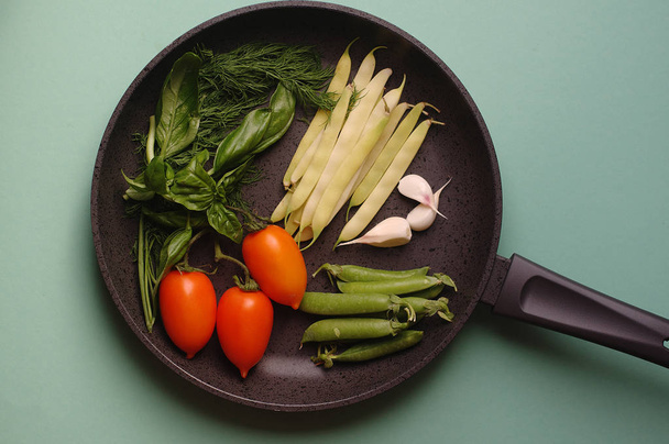 organic fresh vegetables courgette, tomato, asparagus, basil, dill, green peas, garlic in a frying pan - 写真・画像