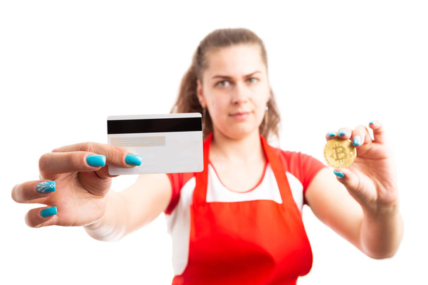 junge Supermarkt- oder Supermarktangestellte mit Kreditkarte und Bitcoin als sicherem Zahlungsmittel, isoliert auf weißem Hintergrund - Foto, Bild
