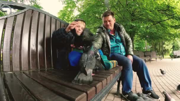 Homel, Wit-Rusland. Vader en zoon gevoed wilde duiven in het park. - Video