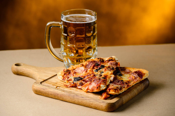 Slice of delicious homemade pizza served with light cold beer on - Foto, Bild