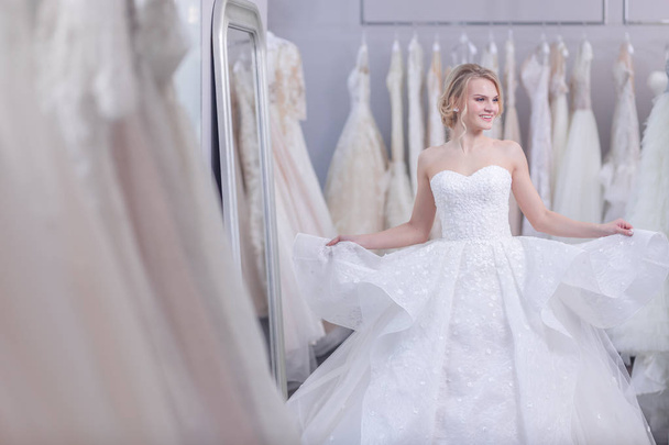Щаслива приваблива жінка в білій сукні в весільному магазині
 - Фото, зображення