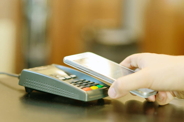 Мобильная оплата в кафе со смартфоном NFC рядом с полевой технологией беспроводной связи
. - Фото, изображение