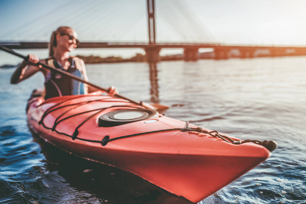 Attractive young woman is kayaking on sunset. Canoeing alone. - 写真・画像