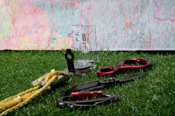 on a green background and maps, lie tourist set, compass, knife, rope, carabiner to climb the mountains - Foto, Imagen