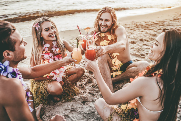 Cheers! Group of young attractive friends are having fun on beach and drinking cocktails. Party in Hawaiian style. - Φωτογραφία, εικόνα