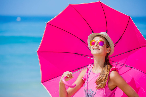 Menina com um guarda-chuva rosa na praia de areia
 - Foto, Imagem