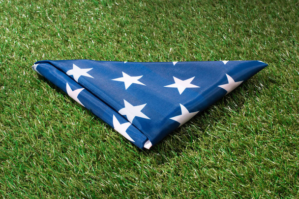 close up view of folded american flag on green lawn, americas independence day concept - Photo, Image