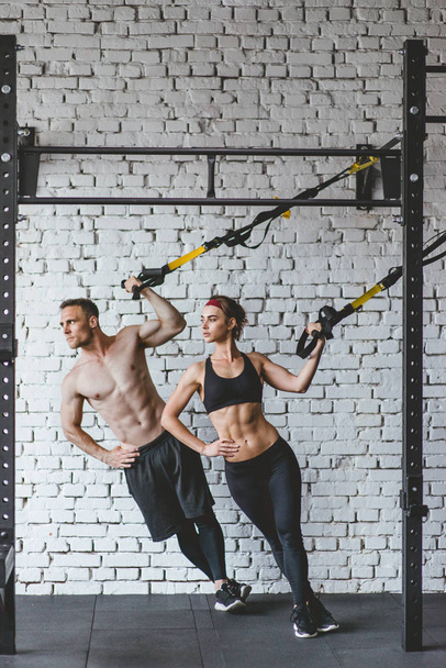 junges sportliches Paar trainiert im Fitnessstudio. trx-Konzept. - Foto, Bild