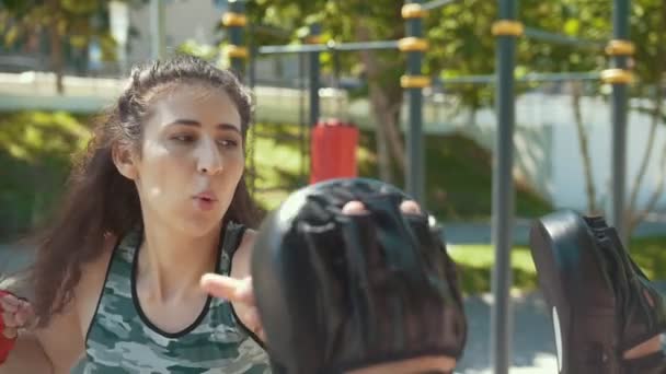Joven hombre enseña hermosa mujer boxeo golpes al aire libre en día soleado
 - Metraje, vídeo