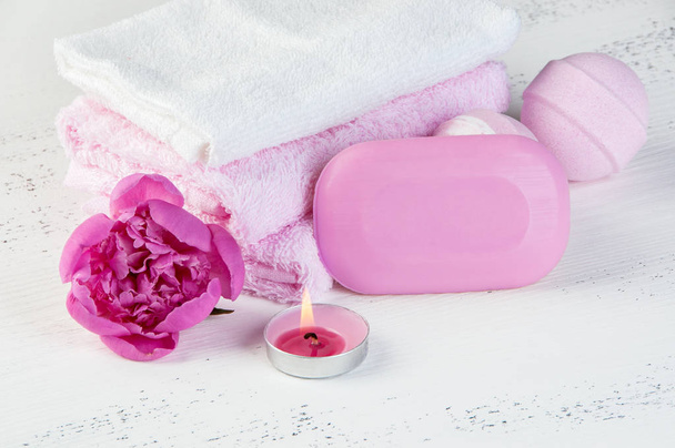 Ροζ λευκή σύνθεση σπα με μπανιέρα βόμβες, σαπούνι, ροζ παιωνία, πετσέτες και άρωμα κεριού στο shabby λευκό φόντο με υφή. Χώρο αντίγραφο για το κείμενο - Φωτογραφία, εικόνα