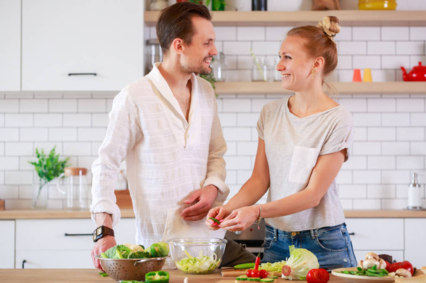 Fotoğraf güzel erkek ve kadın mutfakta sebze yemek - Fotoğraf, Görsel