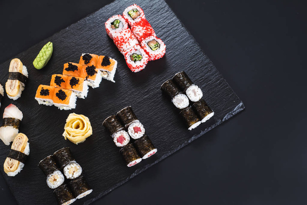 A set of different sushi rolls with caviar on black background - Фото, зображення