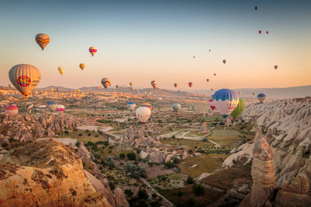 Гореме, Каппадокия, Турция - 10 июня 2018 года: вид красочных воздушных шаров, летящих над Красной долиной на восходе солнца
. - Фото, изображение
