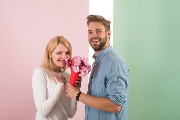 Man congratulates woman birthday anniversary holiday, pastel background. Couple in love celebrating holiday. Man gives bouquet flowers to girlfriend. Gift concept. Couple date bouquet flowers gift - Φωτογραφία, εικόνα