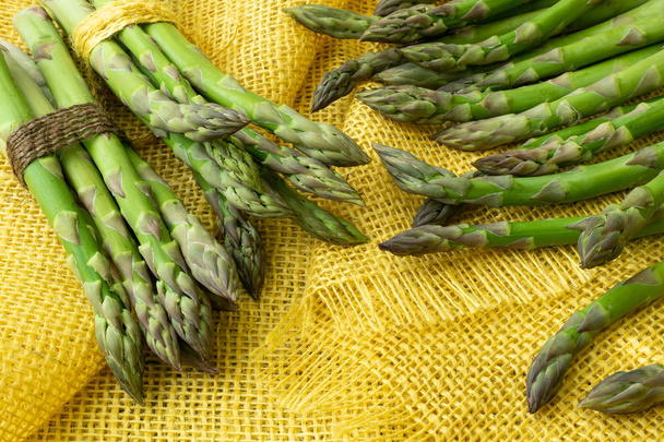 Bunches of asparagus tied with twine on a burlap background. Asparagus officinalis. - Photo, Image