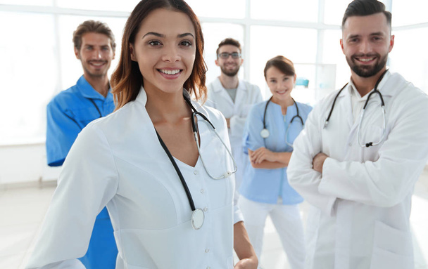Attractive female doctor with medical stethoscope in front of medical group - Photo, image