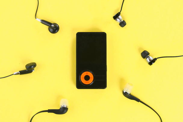 MP3 Player with Headphones on pastel yellow background. Minimalism - Zdjęcie, obraz