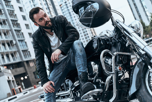 handsome rockabilly motorcyclist man sitting on motorbike  - 写真・画像