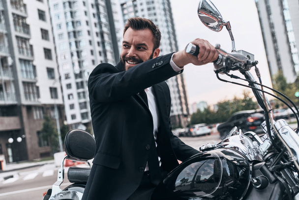 elegant man in suit smiling while sitting on motorbike outdoors - Foto, Bild