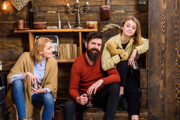 Man and ladies on happy faces discussing and drinking mulled wine. Friends have fun, speaking and drinking hot drinks in wooden interior. Friends spend leisure in cozy interior. Soulmates concept - Photo, image