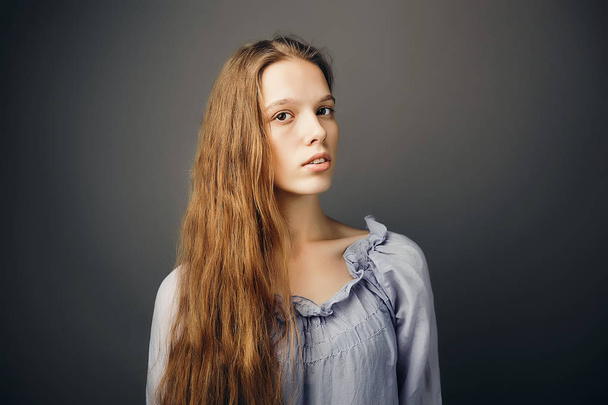 Portrait de jeune femme aux longs cheveux roux ondulés sans maquillage
 - Photo, image
