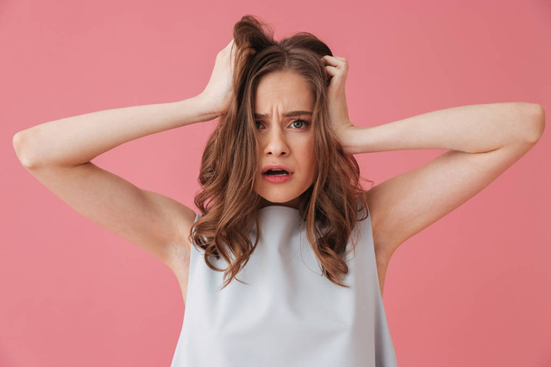 Image of shocked young woman standing isolated over pink background looking aside. - Foto, Imagem