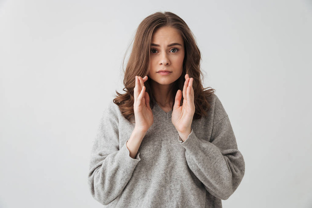 Image of Surprised brunette woman in sweater looking at the camera over grey background - Valokuva, kuva