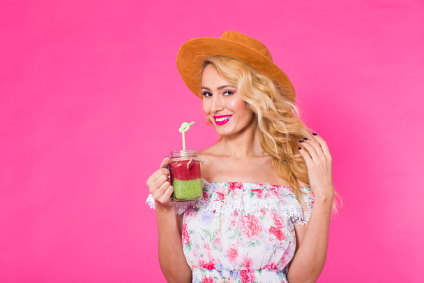 Portrait de jeune femme tenant et buvant un délicieux smoothie vert milkshake sur fond rose
 - Photo, image