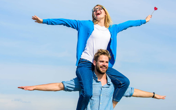 Freedom concept. Couple in love enjoy feeling freedom outdoor sunny day. Man carries girlfriend on shoulders, sky background. Lovers enjoy date and feeling free. Couple happy date having fun together - Photo, Image
