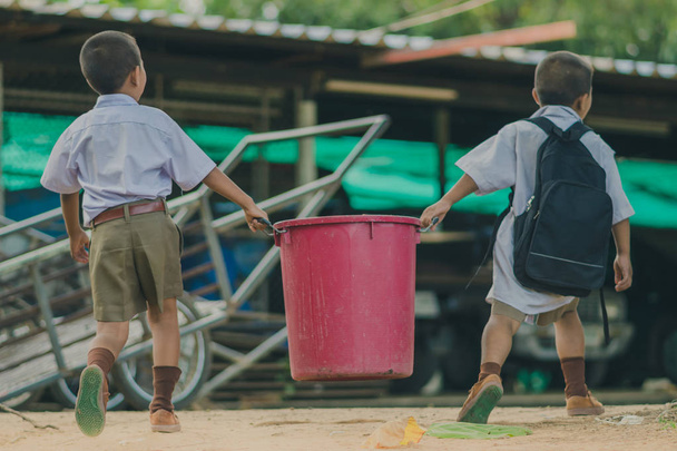 Schüler helfen, Müll aus dem Klassenzimmer zu entfernen, um ihn zu stapeln. - Foto, Bild
