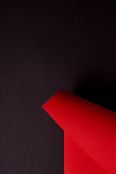 Curled red paper sheet on black background - Fotó, kép