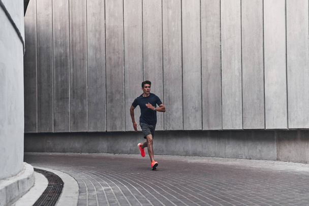 full length of handsome sportive young man running in city street  - Fotoğraf, Görsel